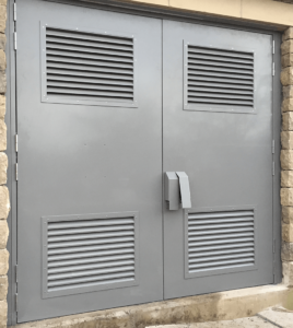 Grey steel security door with louvres.