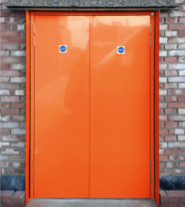 Orange steel fire door with a brick surround.